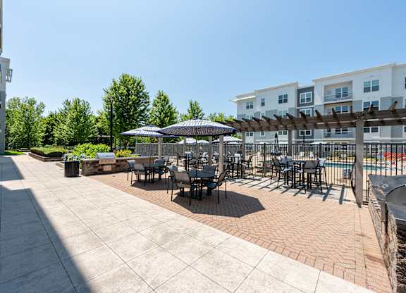 A patio with tables and chairs is surrounded by apartment buildings.