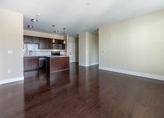 A kitchen with dark wood floors and white walls.