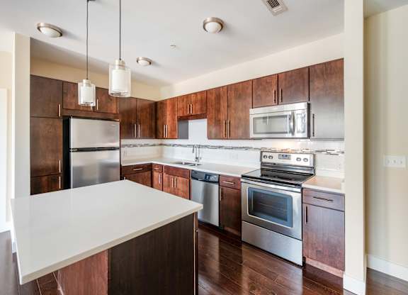 A kitchen with a white counter top and stainless steel appliances.