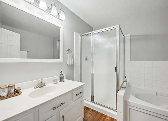 Model Bathroom with White Cabinets and Wood-Style Flooring at Dulles Green Apartments located in Herndon, VA.