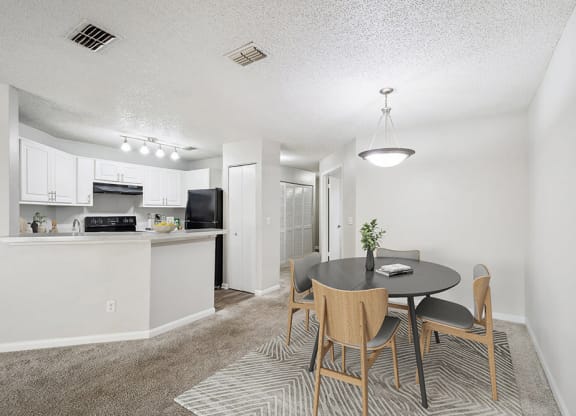 Model Dining Room with Carpet and View of Kitchen at Westland Park Apartments in Jacksonville, FL.