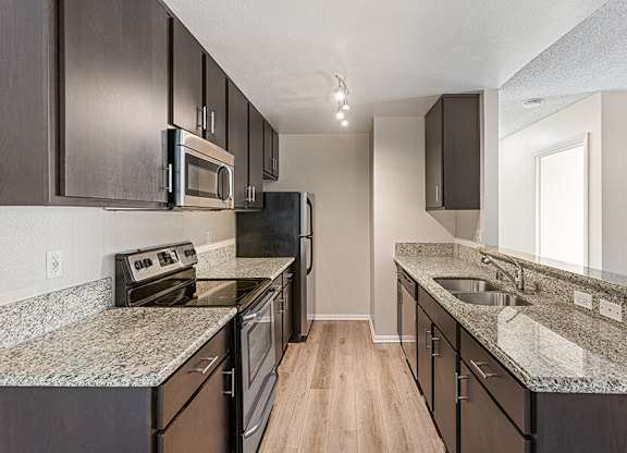 Model Kitchen with Dark Wood Cabinets and Wood-Style Flooring at Santa Fe Ranch Apartments located in Carlsbad, CA.