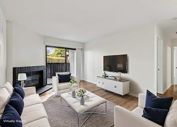 A living room with a fireplace, a white couch, and a television.