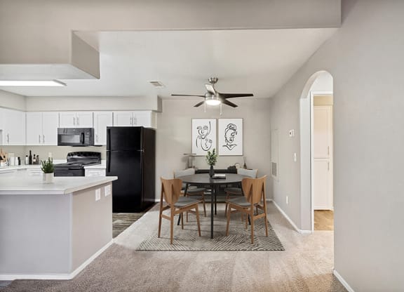 Model Dining Room with Carpet and View of Kitchen at Verraso Apartments in Las Vegas, NV.