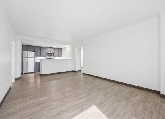 A spacious room with wooden flooring and white walls.