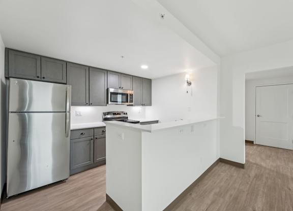 A kitchen with a refrigerator, microwave, and oven.