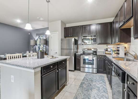 Model kitchen with a large island and stainless steel appliances.