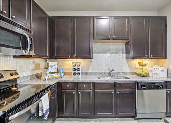 Model kitchen with dark brown cabinets and stainless steel appliances.