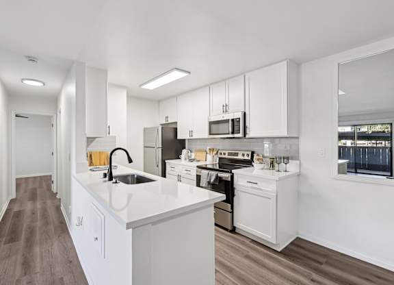 A modern kitchen with white cabinets and appliances.