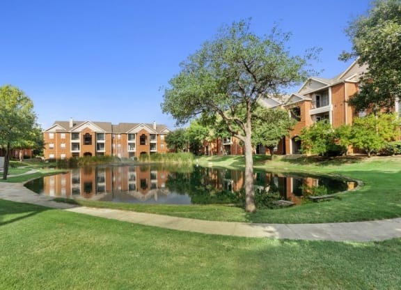 Catch and release fishing pond between apartment buildings with walking path in front.