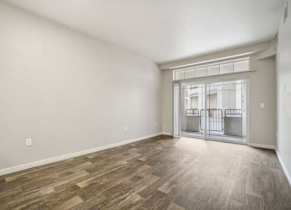 Model Living Room with Wood-Style Flooring and Patio Accessibility at Altitude on Fifth Apartments located in Salt Lake City, UT.