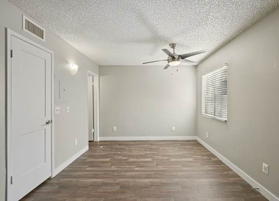 A room with a ceiling fan and wood-style flooring.