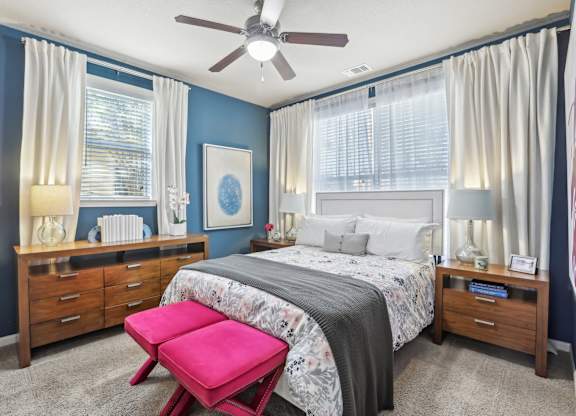 Model bedroom with queen bed and blue accent wall.
