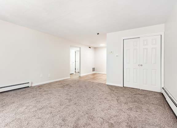 A spacious room with a carpeted floor and white walls.