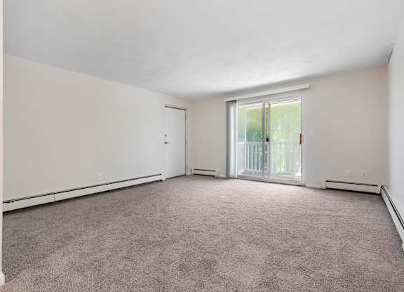 A large empty room with a carpeted floor and a sliding glass door.