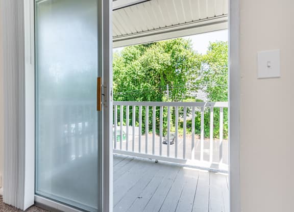 A glass door opens to a balcony with a white railing.