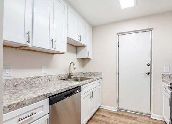 A kitchen with white cabinets and a marble countertop.