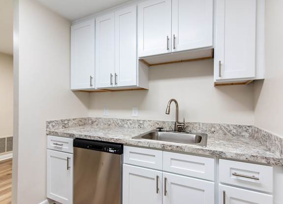 A kitchen with white cabinets and a granite countertop.