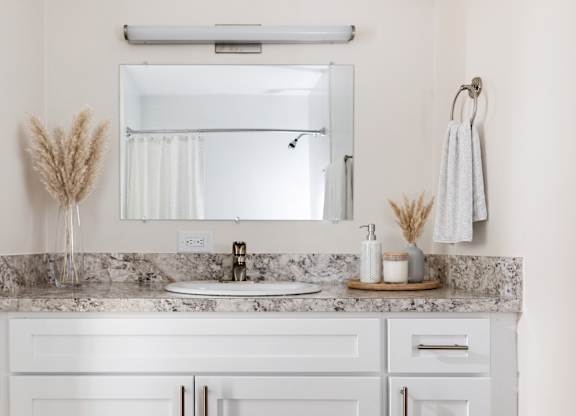 A bathroom with a marble countertop and white cabinets.
