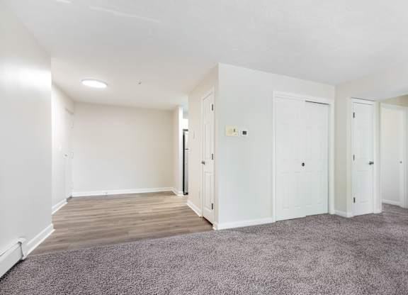 A room with white walls and a grey carpet.