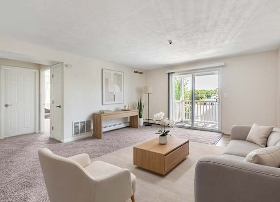 A living room with a white sofa, a white chair, a wooden coffee table, and a white door.