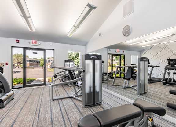 A gym with a variety of equipment including treadmills, weights, and exercise machines.