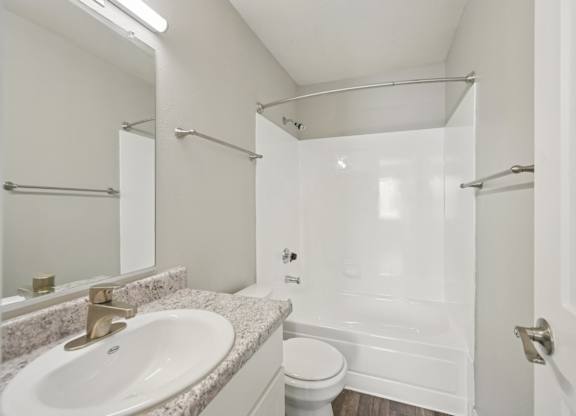 Model white bathroom with a sink, toilet, and shower.