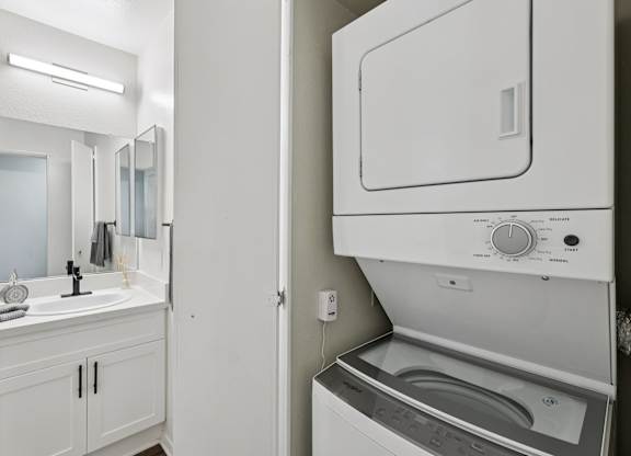 A white bathroom with a washer and dryer built into the wall.