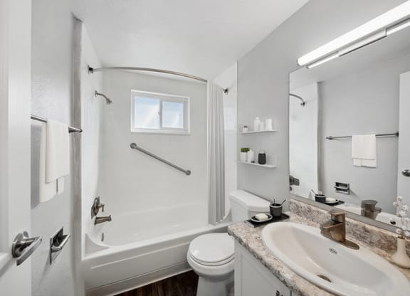 Model Bathroom with White Cabinets, Wood-Style Flooring and Shower/Tub at Esprit at Cherry Creek Apartments in Glendale, CO.