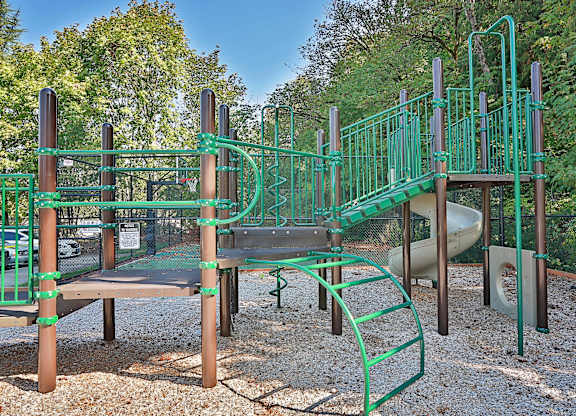 A playground with a green slide and a brown wooden platform.