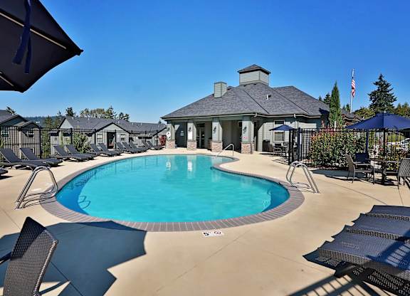 A large outdoor swimming pool surrounded by lounge chairs and umbrellas.