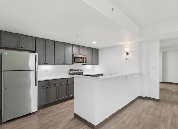 A modern kitchen with a stainless steel refrigerator and wooden flooring.