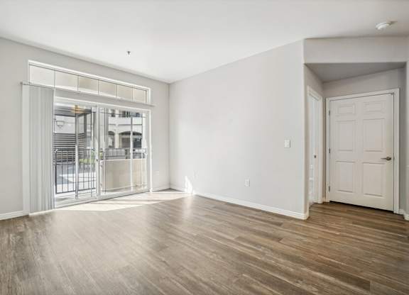 Model Living Room with Wood-Style Flooring and Patio Accessibility at Altitude on Fifth Apartments located in Salt Lake City, UT.