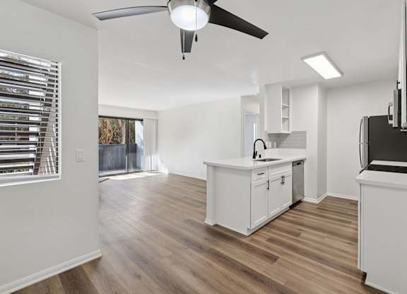 A kitchen with white cabinets and a wooden floor.
