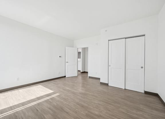A room with white walls and wooden flooring with a rug on the floor.