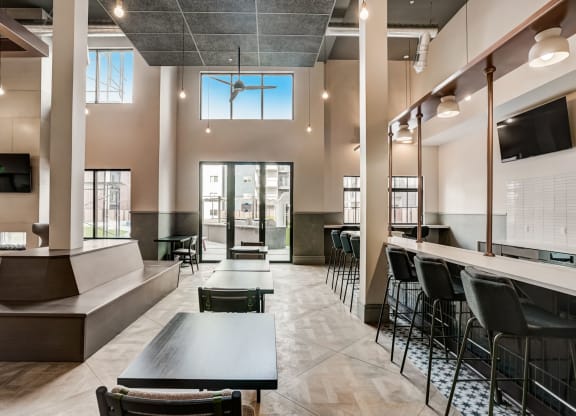 a large lobby with tables and chairs and a bar with chairs