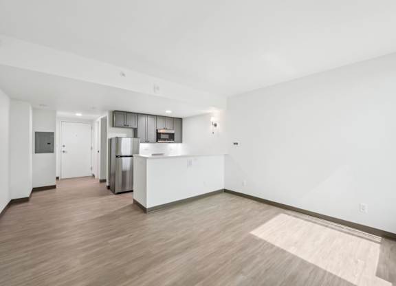 A kitchen with white cabinets and a wooden floor.