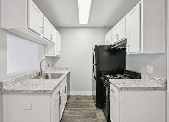 Model kitchen with a black refrigerator and white cabinets.