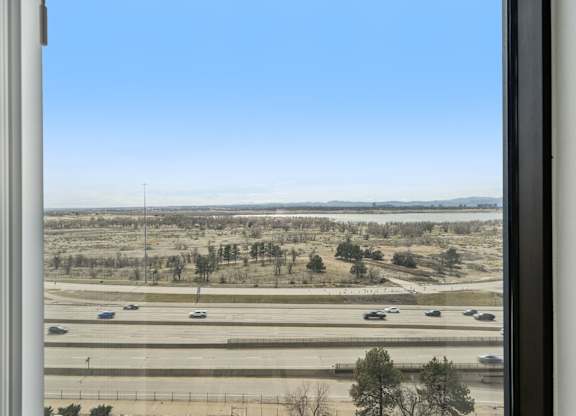 A view from a window looking out onto a highway with cars on it.