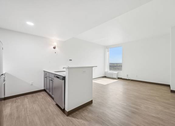 A kitchen with white cabinets and a wooden floor.
