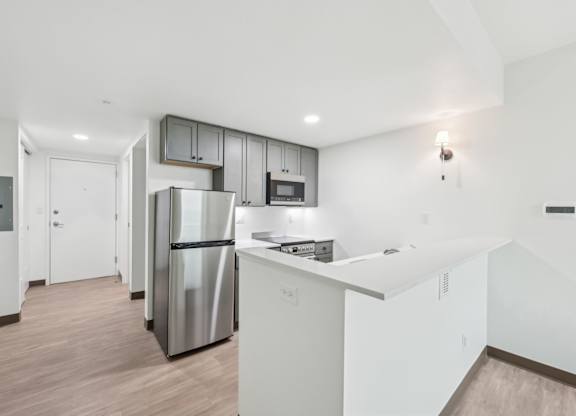 A kitchen with a stainless steel refrigerator and white cabinets.