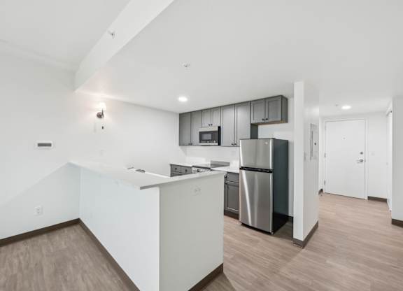 A modern kitchen with a white countertop and stainless steel appliances.