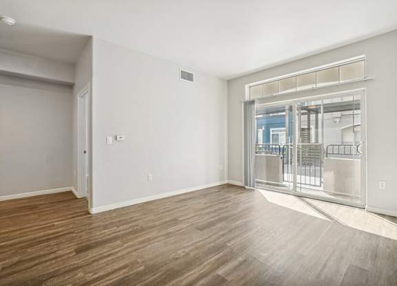 Model Living Room with Wood-Style Flooring and Patio Accessibility at Altitude on Fifth Apartments located in Salt Lake City, UT.