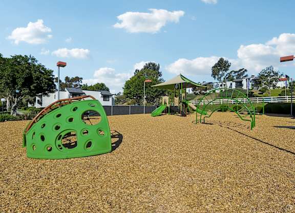 A playground with a green slide and a red flag.