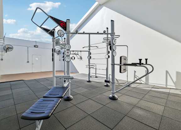 A gym with a bench, weights and exercise equipment.