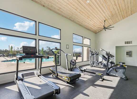 A gym with treadmills, exercise bikes, and a fan.