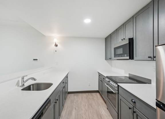 A modern kitchen with stainless steel appliances and wooden flooring.