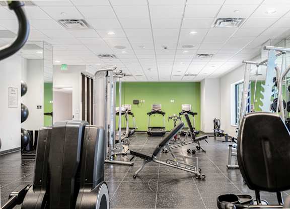 A gym with a variety of equipment including treadmills, weights, and exercise machines.