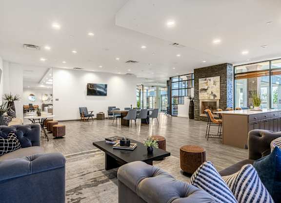 A modern living room with a variety of seating options and a flat screen TV mounted on the wall.