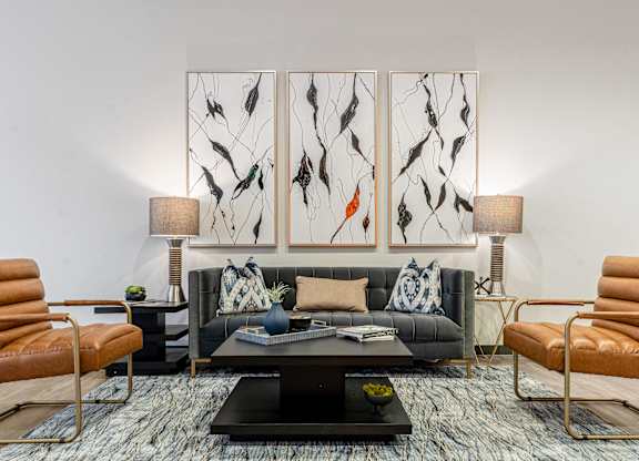 A living room with a black couch, a coffee table, and two chairs.